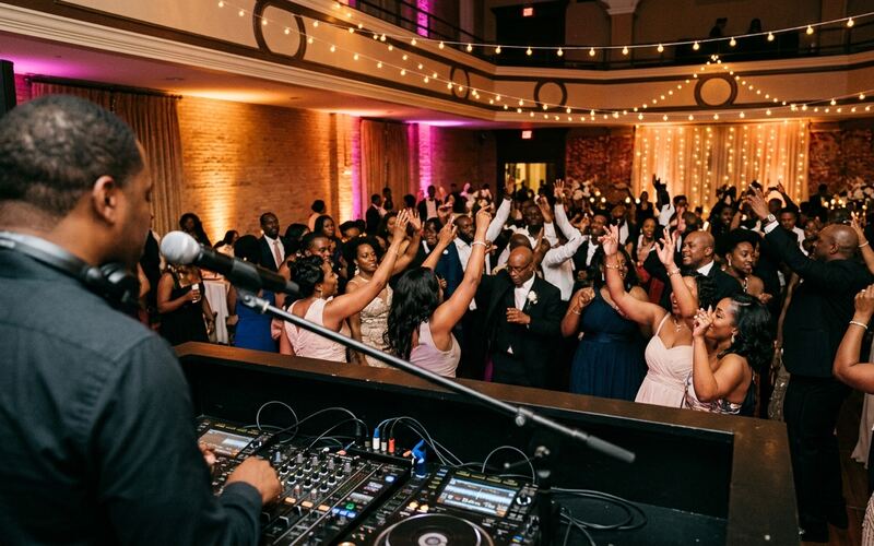 View from behind the DJ booth and microphone out to a packed wedding dance floor